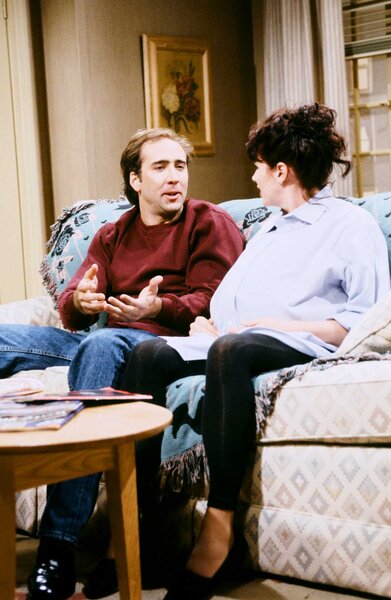 Nicolas Cage talking with Julia Sweeney talking on a couch during Saturday Night Live Season 18 Episode 1.
