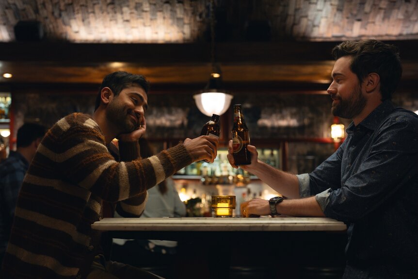 Naveen (Kapil Talwakar) and Rob (Jack Whitehall) cheers at a bar on The 'Burbs Season 1.