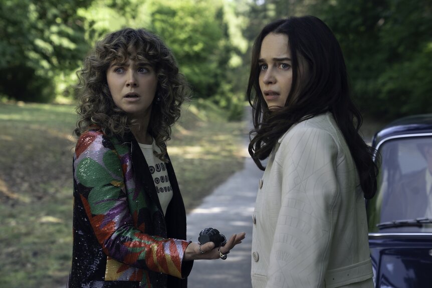 Twila (Haley Lu Richardson) and Bea (Emilia Clarke) stand outside a vechicle on Ponies Episode 108.